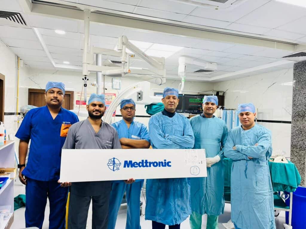Cardiologists in surgical scrubs standing in a hospital operating room.